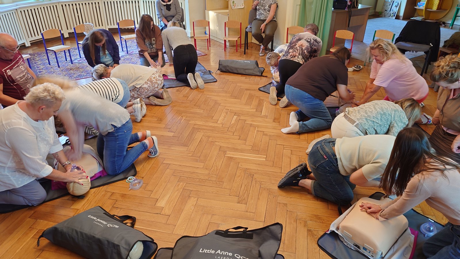 Grupa uczestników ćwiczy resuscytację na parkiecie