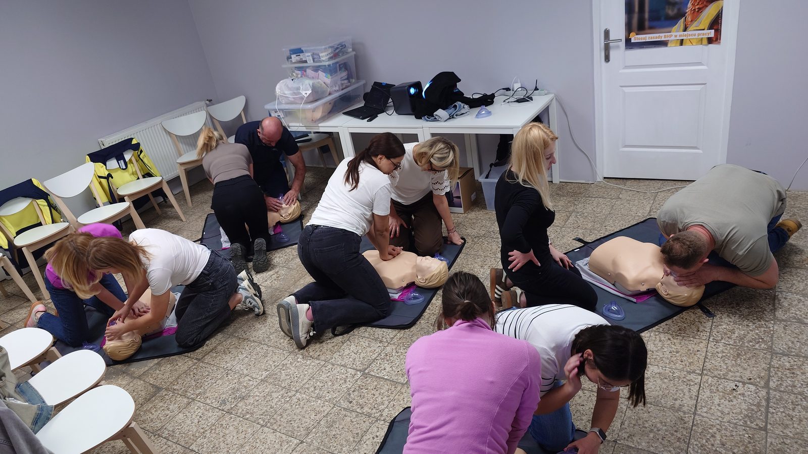 Pracownicy ćwiczą resuscytację przy kilku stanowiskach z fantomami
