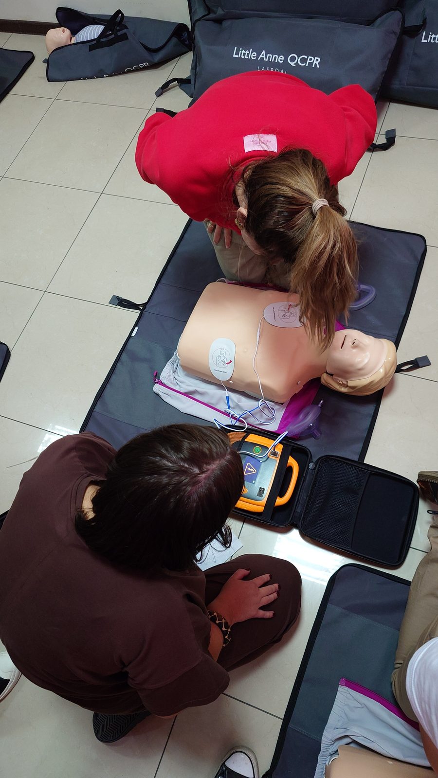 Dwie uczestniczki ćwiczą RKO i podłączenie elektrod AED